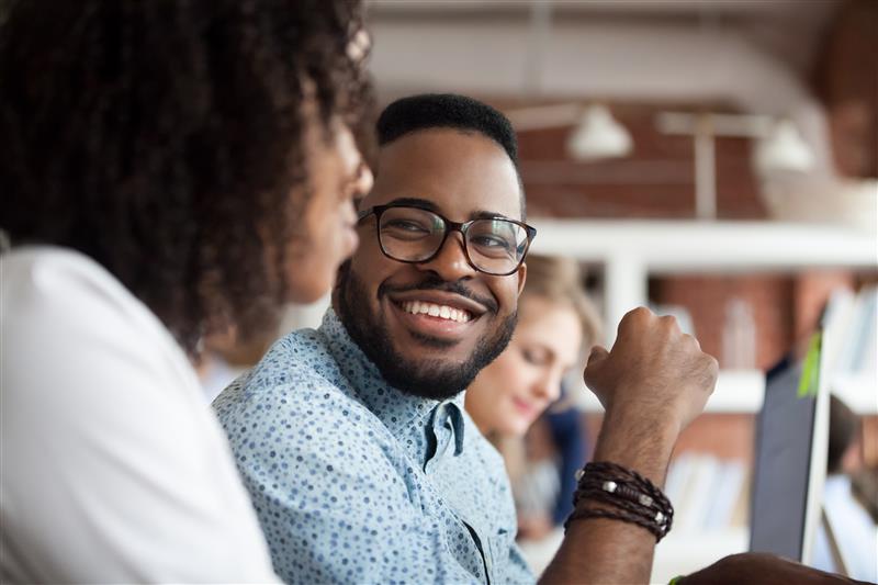 Man with glasses smiling a the woman sitting next to him.