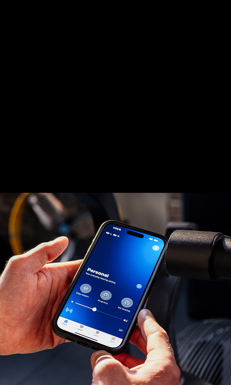 Hands holding a cell phone with the My Starkey app on screen.