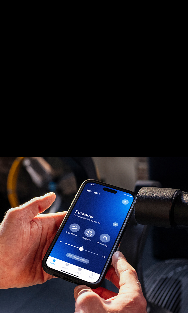 Hands holding a cell phone with the My Starkey app on screen.